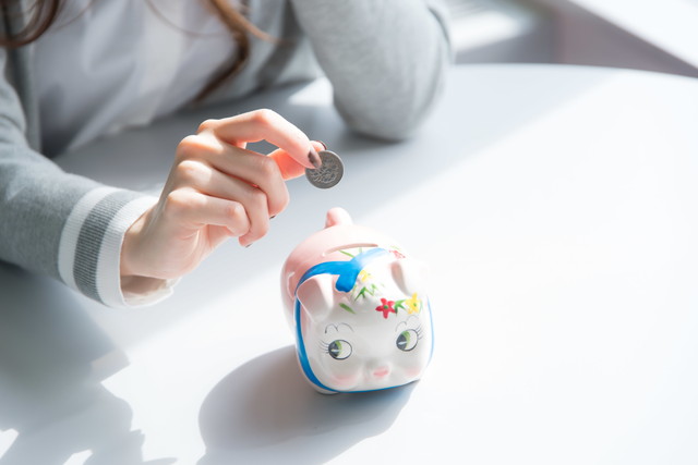 貯金箱に硬貨を入れる女性の手