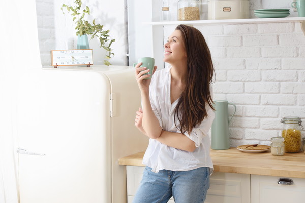 朝のキッチンでコーヒーを飲む若い幸せな女性